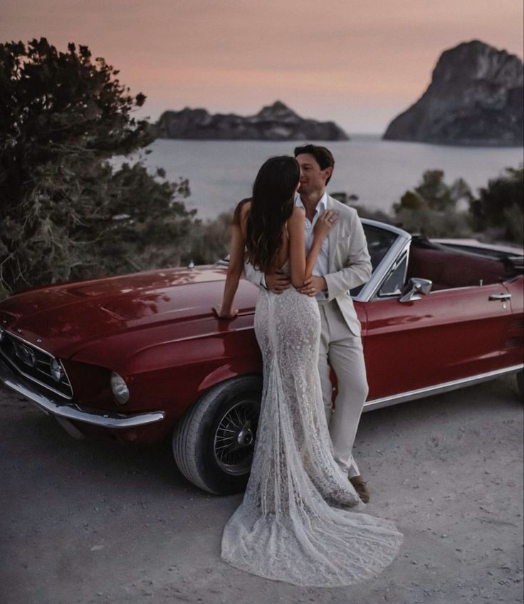 Couple embracing beside a vintage convertible at sunset by the sea